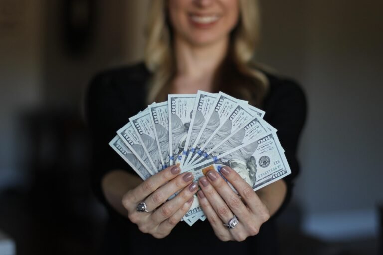 Woman smiling confidently while holding a fan of cash in her hands