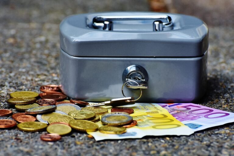 Scattered coins and euro bills beside an open cash box